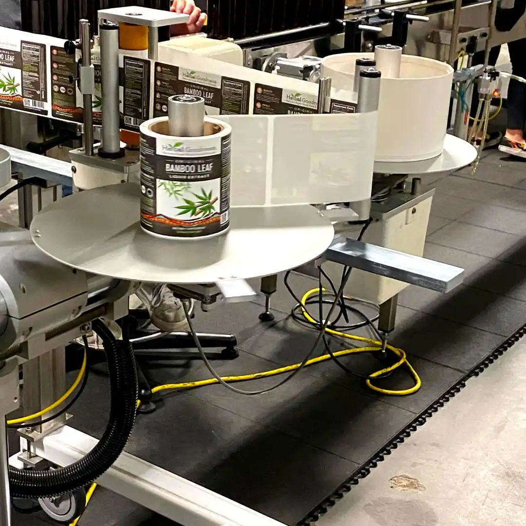 Automated labeling machine with white circular platforms and product containers.