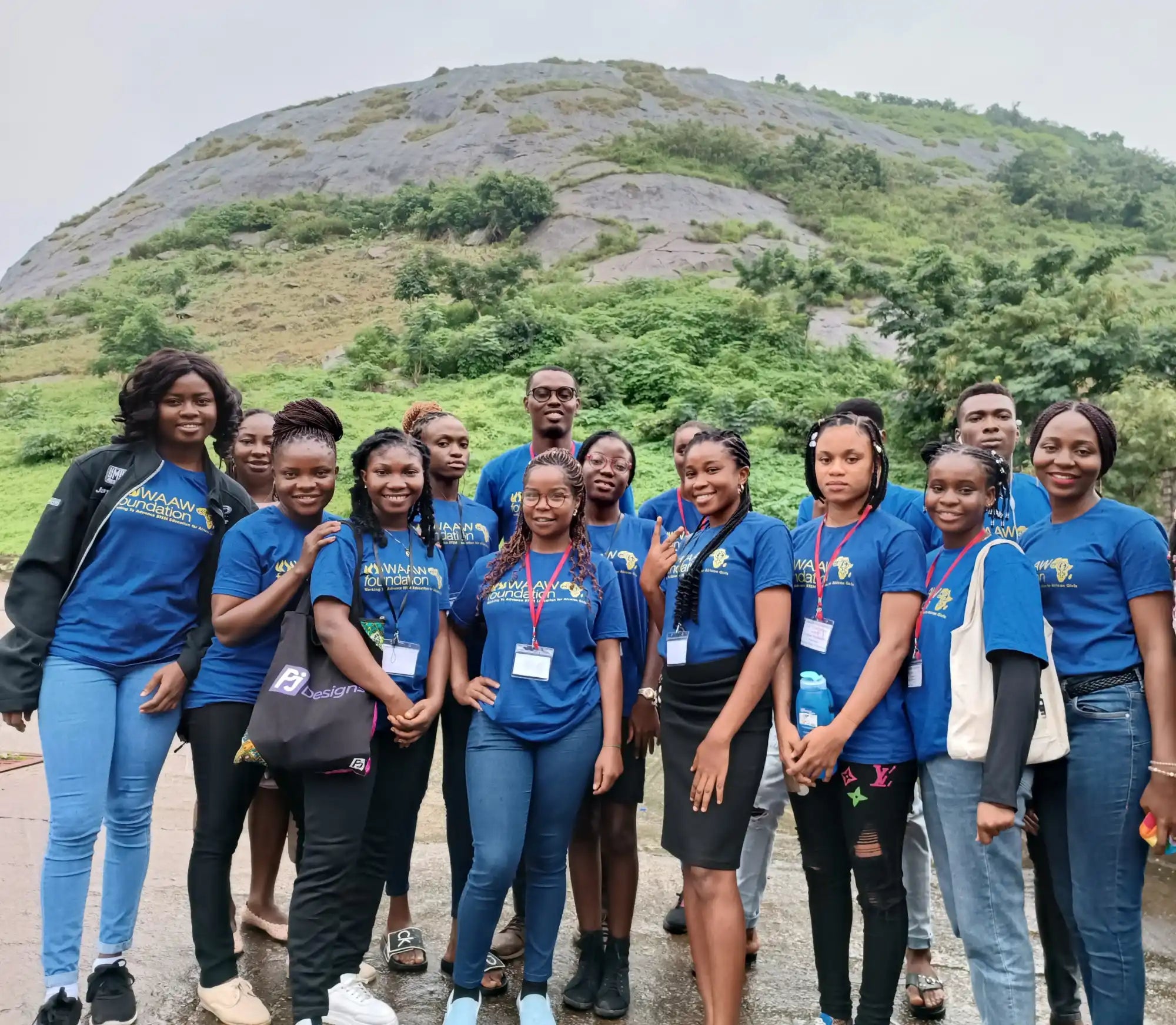 A group wearing matching blue t-shirts posing together outdoors.