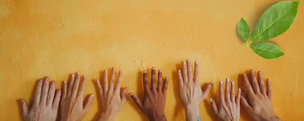 Multiple hands reaching upward against an orange wall with a few green leaves visible.